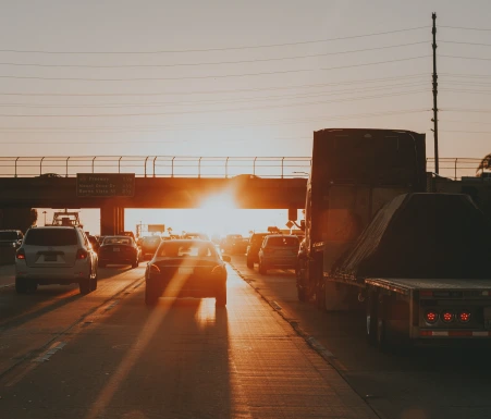 Cars driving down highway towards sunset