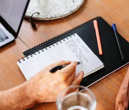 Person writing a checklist on a notepad