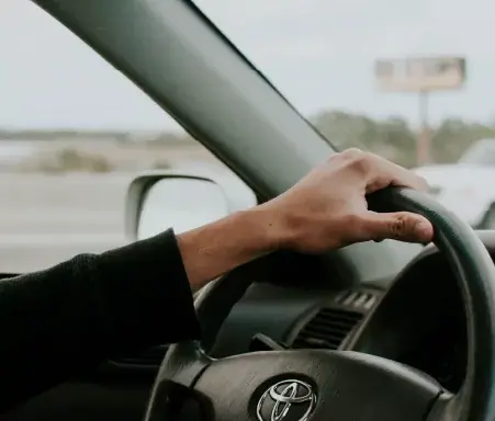Toyota steering wheel with hand on it driving