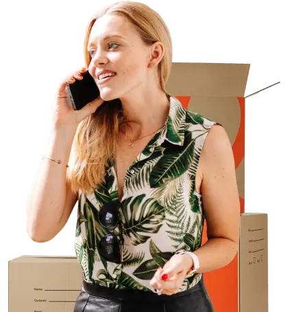 Woman talking on the phone booking a removalist moving boxes behind her