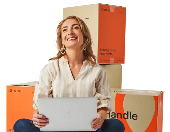 Woman sitting on floor booking a removalist with moving boxes behind her