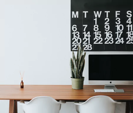 Office desk with computer screen and calendar on wall