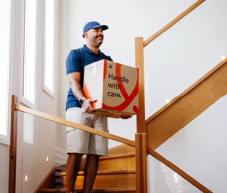 Removalist carefully carying a box down stairs