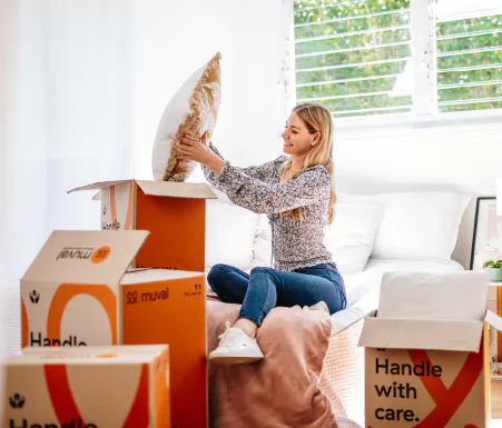 Woman sitting on her bed packing moving boxes